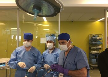 Group of surgeons looking at a screen with scrubs and masks on.
